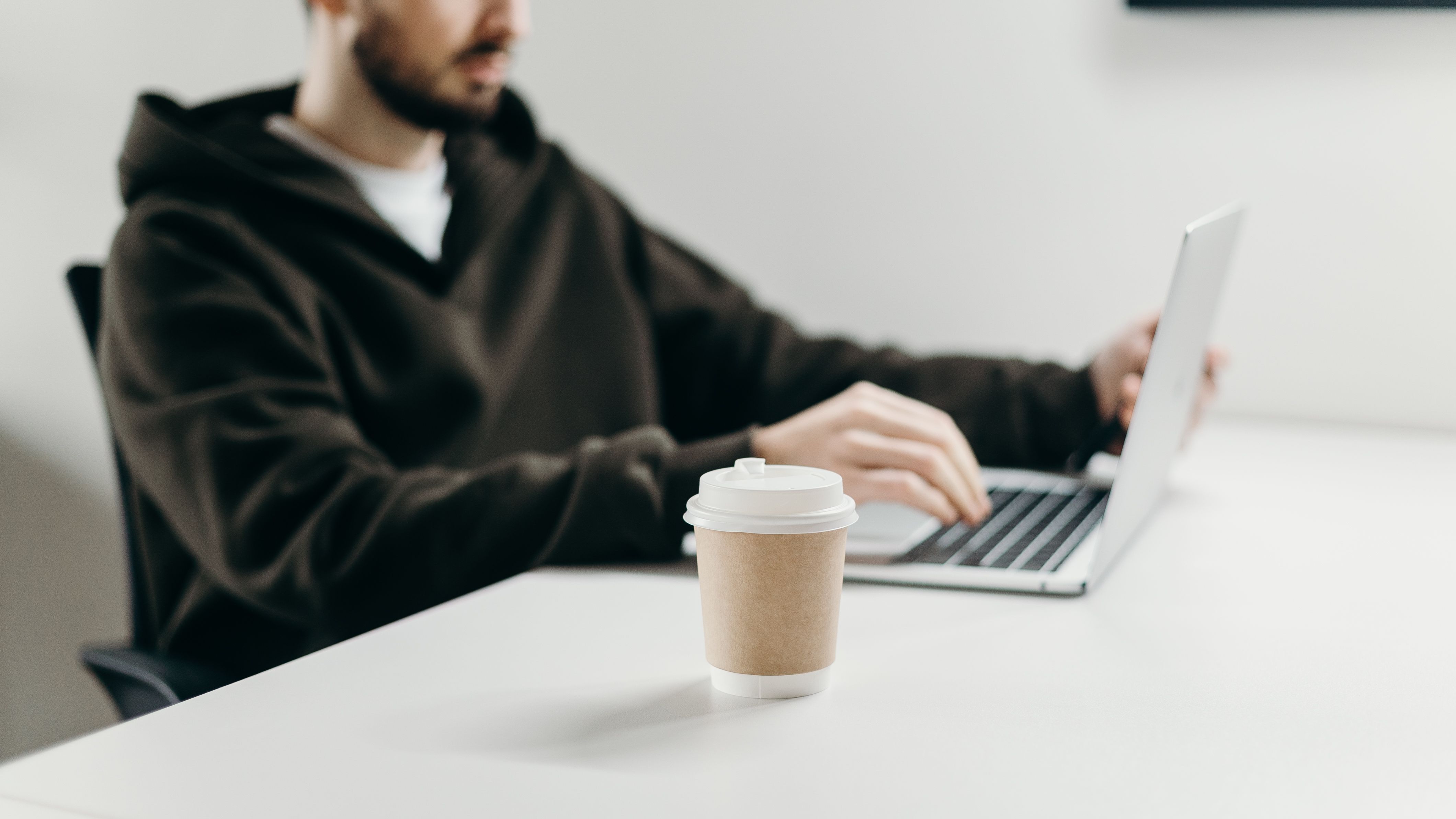 A freelancer working on a laptop at a desk with a coffee cup